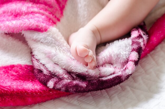 Asian newborn baby's foot on the bed