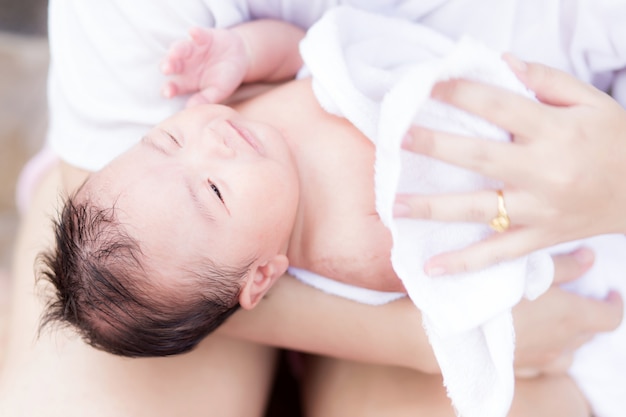 Neonato asiatico nel braccio della madre dopo aver fatto il bagno