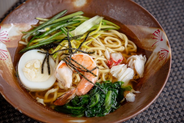 Asian noodle soup with crab meat, boiled egg, shrimp and spinach