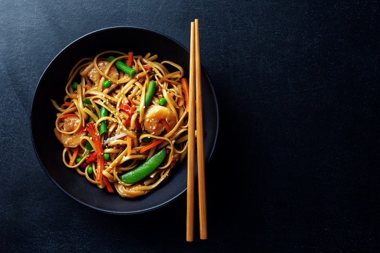 Photo asian noodles with prawns and vegetables served in bowl on dark background.