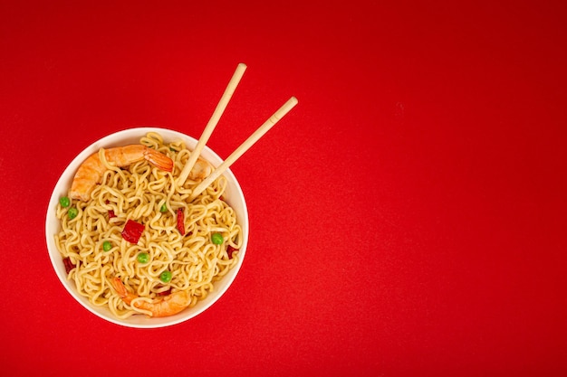 Asian noodles with shrimps in bowl minimal red background