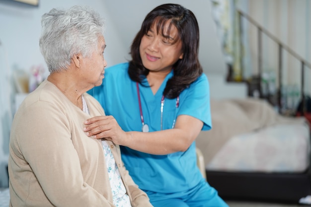 Asian nurse care, help and support senior woman patient at hospital.