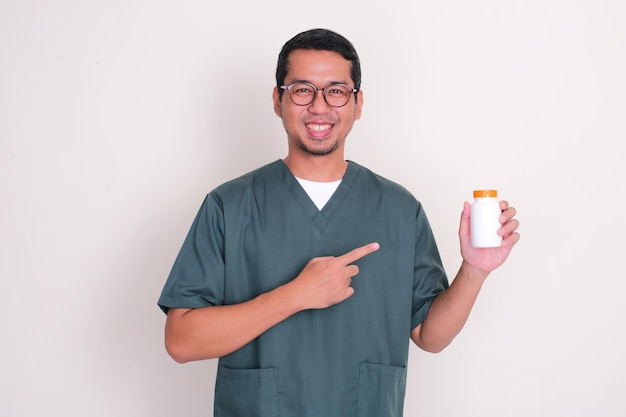 Photo asian nurse man smiling and pointing to medicine bottle that he hold