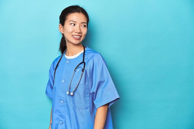 Photo asian nurse with stethoscope medical studio shot looks aside smiling cheerful and pleasant