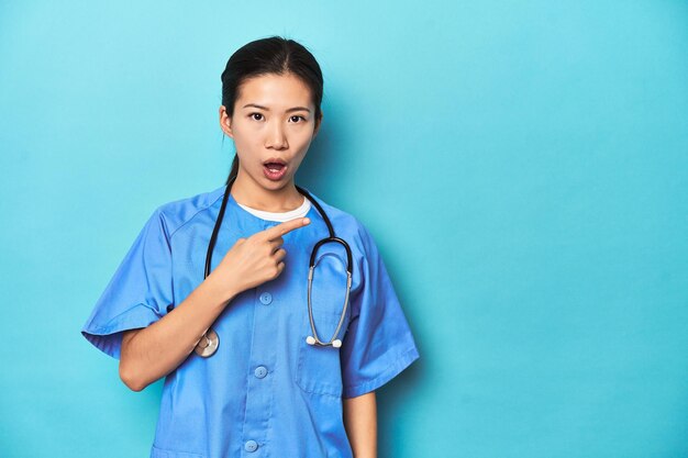 Asian nurse with stethoscope medical studio shot pointing to the side