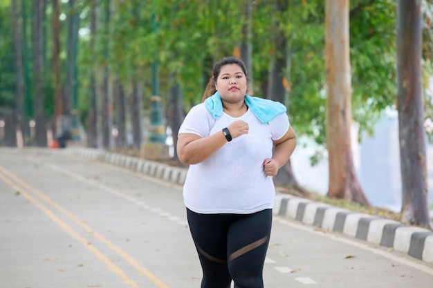 아시아의 비만한 여성이 도로에서 달리고 있습니다.