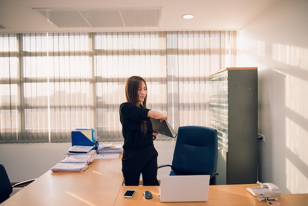 Asian officer woman stretching body at the desk of office