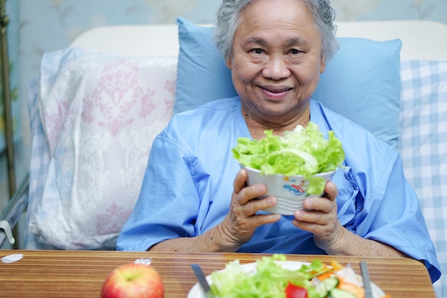 Paziente anziano della donna anziana che tiene alimento sano.