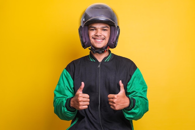 Asian online taxi driver motorbike man wearing helmet and jacket showing thumb up over yellow backgr