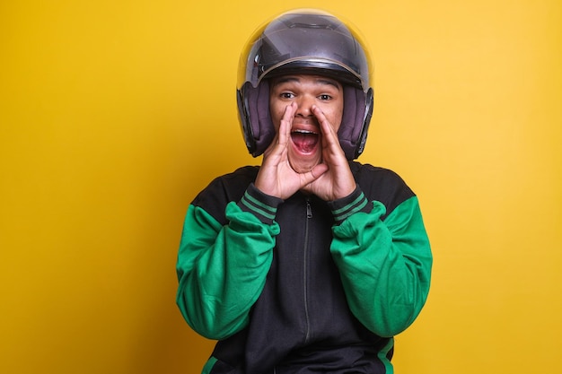 Asian online taxi driver motorbike man with shout gesture or making announcement isolated over yello