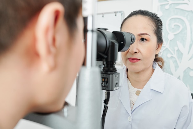 Foto optometrista asiatico che esamina il paziente