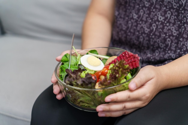 Азиатская женщина с избыточным весом, соблюдающая диету Потеря веса, употребляющая в пищу свежий свежий домашний салат Концепция здорового питания