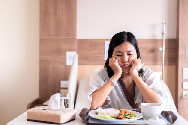 写真 不幸で退屈な食事を感じているアジアの患者の女性、食欲不振、食べ物に飽きている