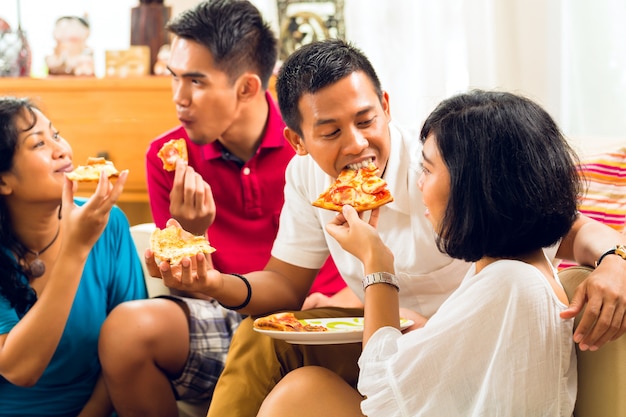 パーティーでピザを食べるアジアの人々