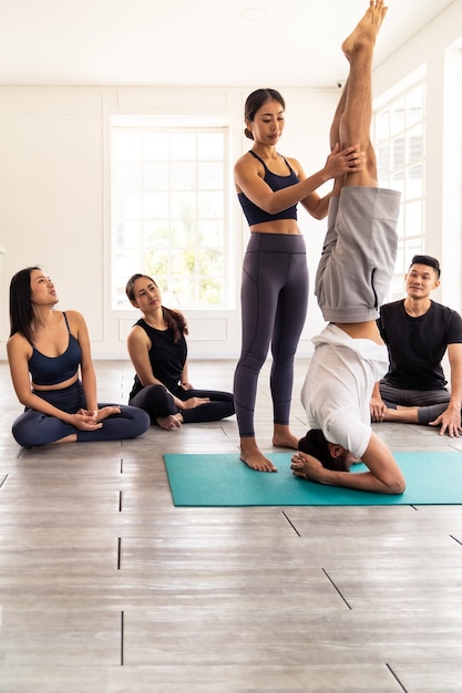 Foto persone asiatiche che imparano lezione di yoga nel fitness club.