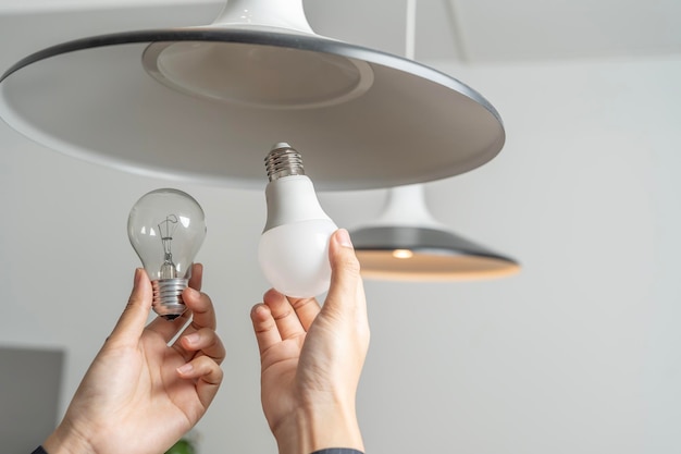 Gli asiatici sostituiscono le lampadine fluorescenti cfl con nuove lampadine led le mani delle donne avvitano una lampadina led a risparmio energetico