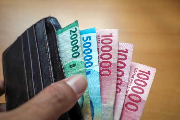 An Asian people take Indonesian money rupiah from wallet Saving and giving concept