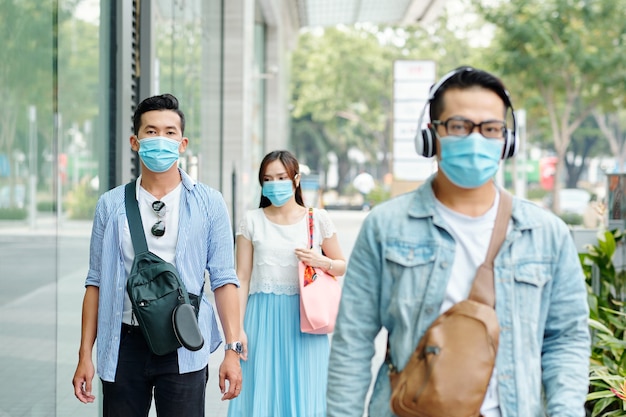 コロナウイルスのパンデミックや汚染された空気のために顔に医療用マスクを付けて街を歩いているアジア人