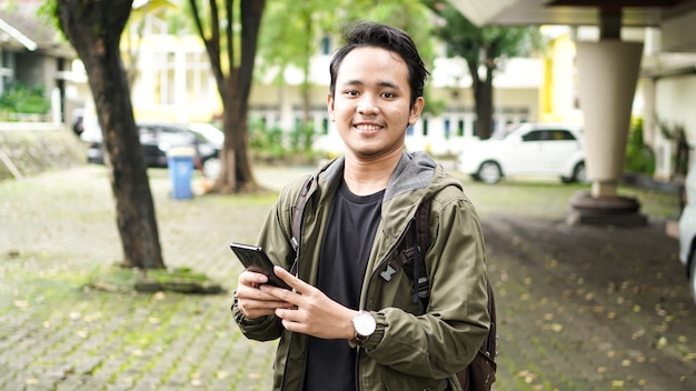 Asian people wear backpacks while holding cellphone