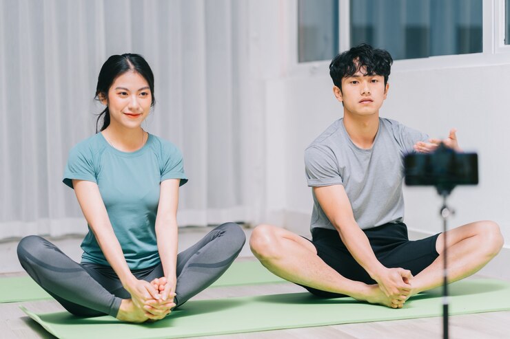 Photo 아시아 개인 트레이너가 학생들에게 요가와 비디오 녹화를지도하여 온라인으로 요가를 가르칩니다.