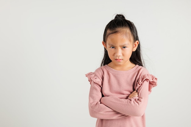 Asian portrait young kid girl standing angry and mad raising fist frustrated and furious while shouting with anger isolated studio shot on white background