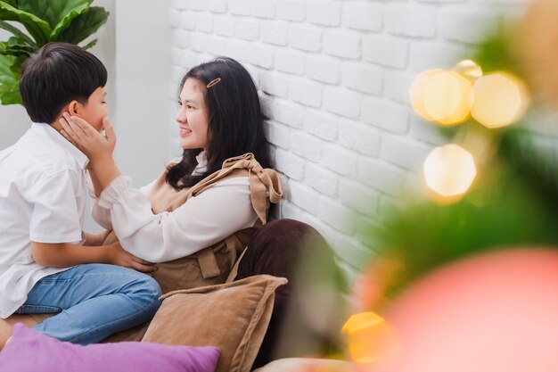 Asian pregnant mother and son sitting together at home with with Christmas tree