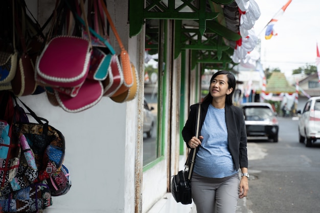 Foto donna incinta asiatica che esamina le borse