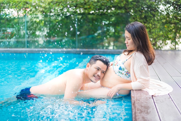 Asian pregnant woman. mom and newborn baby. mother day and\
international women day. relax and recreation with husband at\
swimming pool.