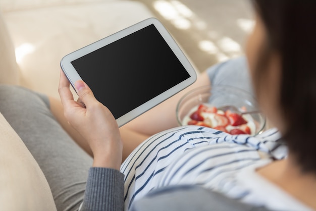 소파에 디지털 태블릿을 사용하여 아시아 임신 한 여자, 높은 각도보기