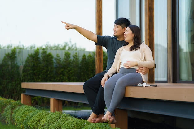Азиатская беременная женщина с мужем разговаривают вместе на террасе дома
