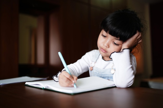 Фото Азиатская девушка дошкольного возраста делает домашнее задание