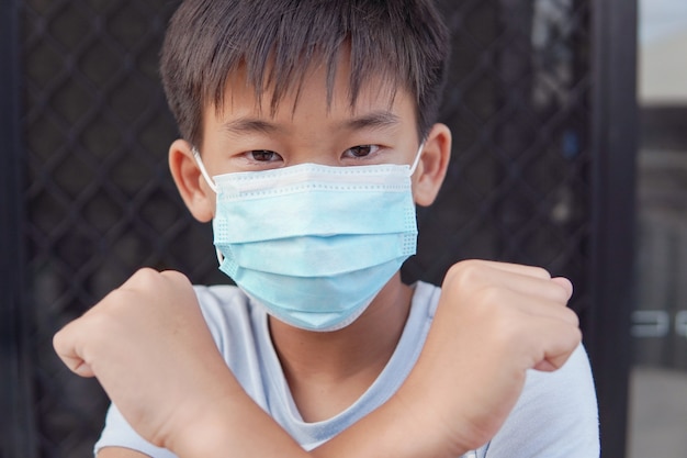 医療用フェイスマスクを着用し、一時停止の標識、自己検疫、コロナウイルス、コビッド19ウイルスの発生流行のパンデミックを作るアジアのプレティーンの少年