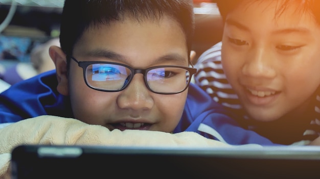 Азиатские preteens смотреть на планшетном компьютере, улыбаться лицо.