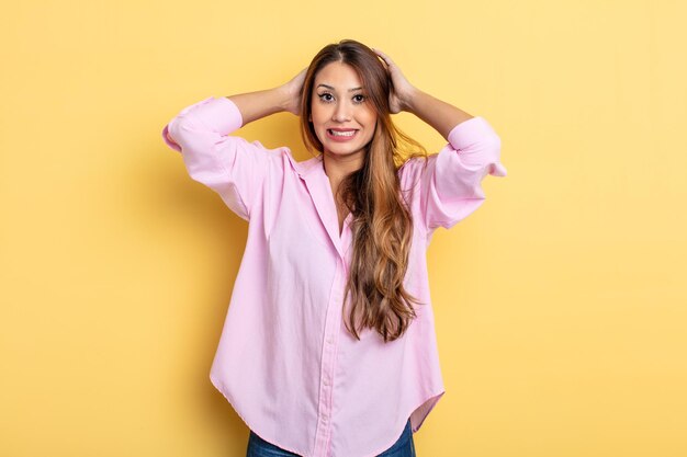 Donna graziosa asiatica che si sente stressata, preoccupata, ansiosa o spaventata con le mani sulla testa in preda al panico per errore