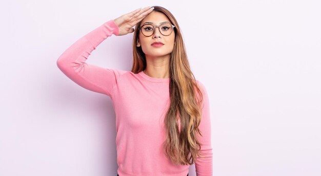 Asian pretty woman greeting the camera with a military salute in an act of honor and patriotism, showing respect