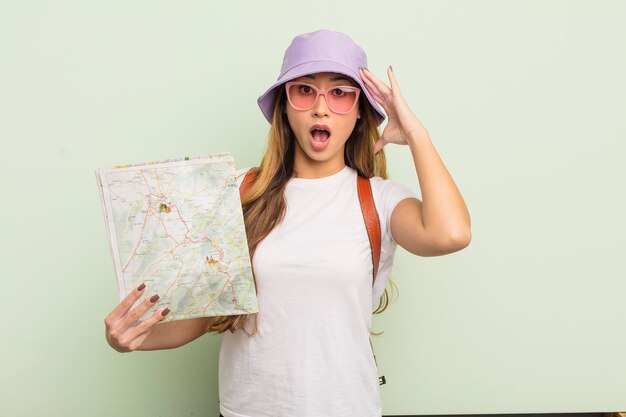 Asian pretty woman looking happy, astonished and surprised. tourist concept with map