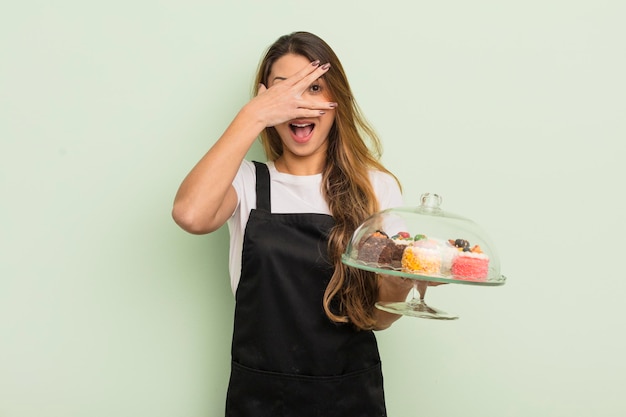 Asian pretty woman looking shocked, scared or terrified, covering face with hand. home made cakes concept