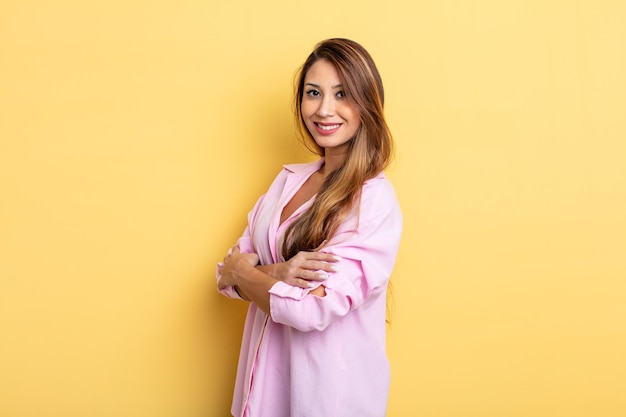 Asian pretty woman smiling to camera with crossed arms and a happy, confident, satisfied expression, lateral view