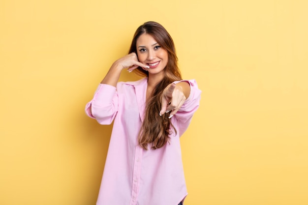 Asian pretty woman smiling cheerfully and pointing to camera while making a call you later gesture talking on phone