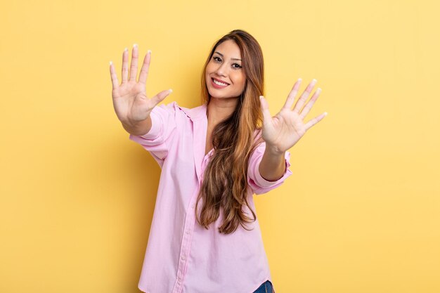 Asian pretty woman smiling and looking friendly, showing number ten or tenth with hand forward, counting down