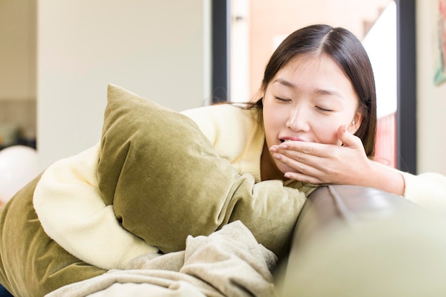 枕とソファで休むアジアのきれいな女性