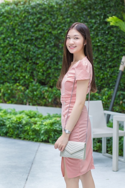 Asian professional business female with long hair is smiling in the garden while looking