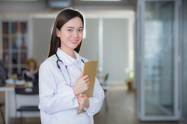 La dottoressa asiatica professionista sorride e sta in piedi con sicurezza tiene in mano gli appunti del documento