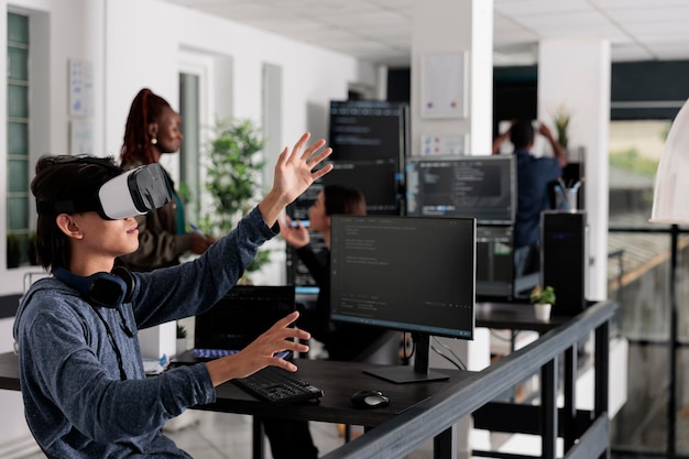 Asian programmer working with virtual reality glasses in it big data office, using vr headset to develop security program. Web developer coding html script with database on computer