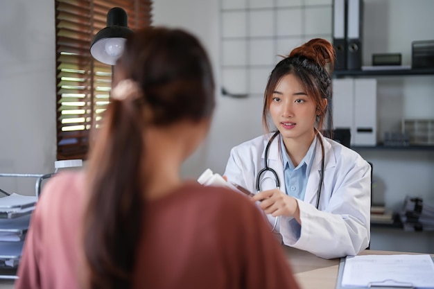 Asian psychologist women showing pills bottle to explaining medicine and prescription to female patient while giving counseling to explaining about mental health therapy to female patient in clinic