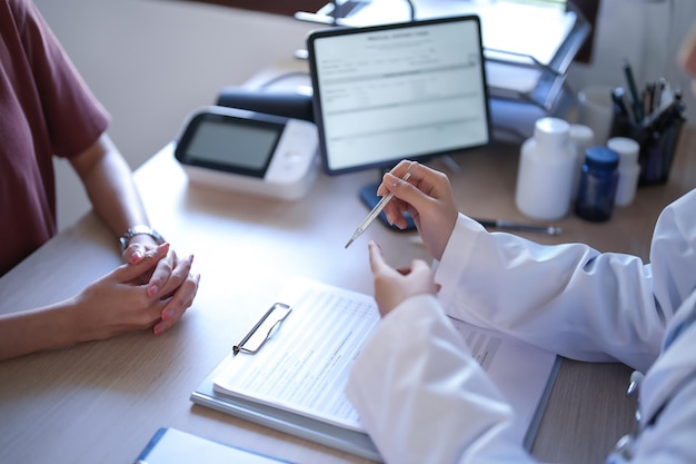 Foto psicologa asiatica che mostra il termometro per spiegare la lettura dei risultati della temperatura sul test della febbre al paziente mentre fornisce consulenza sulla terapia della salute mentale al paziente femminile in clinica