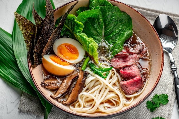 Asian ramen soup with rice noodles mushrooms and pork in black bowl Asian cuisine