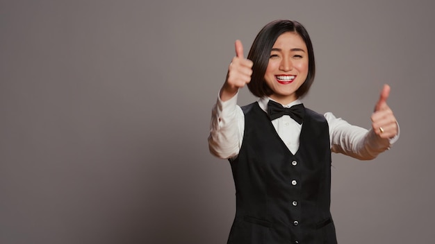 Asian reception staff doing thumbs up symbol on camera