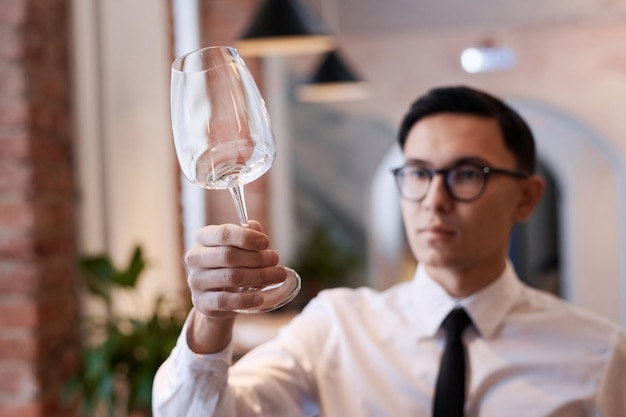 Asian restaurant owner looking at wine glass