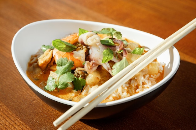 Asian rise with seafood shrimps and octopus with sause in oval plate with bamboo sticks on a wooden table in asian restaurant